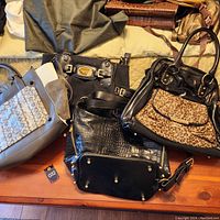 Overview photo showing all 4 purses together on wooden surface and bed, various colors and styles visible