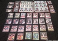 Multiple pages of baseball cards in a binder and loose cards placed on a black surface, shows various players and card designs mostly in color.