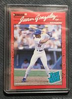 Front of Juan Gonzalez 1990 Donruss baseball card showing player batting in Rangers white uniform with red border and Rated Rookie logo.