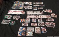 Wide shot of over 100 UFC trading cards spread out on black cloth showing variety of base, inserts, and relic cards.