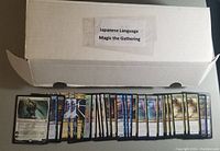 Opened box labeled 'Japanese Language Magic the Gathering' with a row of Magic the Gathering cards showing various card art and Japanese text.