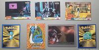 Photo showing 7 Pokémon Topps trading cards laid out flat, depicting various Pokémon characters and scenes, including game tips and character illustrations.