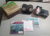Complete lot items including the Model C View-Master stereoscope, original box, light attachment, and New York City reels with sleeve and booklet.