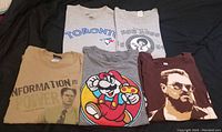 Set of five vintage graphic t-shirts laid flat, showing all shirt fronts and logos.