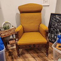 Full front view of the antique armchair showing mustard yellow upholstery and carved wood frame.