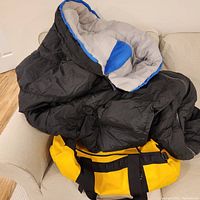 Photo showing Kelti sleeping bag draped over a couch, black exterior with gray and blue interior.