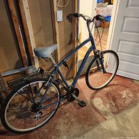 Side view of gray-blue Globe Carmel XL step-through bicycle in basement