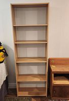 Front view of the Ikea wood veneer bookcase showing five shelves and standing upright against a wall.