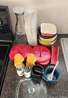 Full view of the kitchen lot showing mixed items grouped on countertop including bowls, brie bakers, shakers, pestle/mortar, carafe and glass dish.