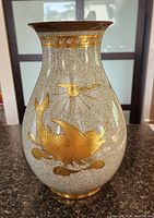 Full view of vase showing a large gold fish design on a crackled white base.
