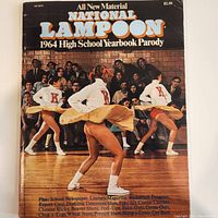 Front cover of the National Lampoon 1964 High School Yearbook Parody showing three cheerleaders kicking with crowd in background.