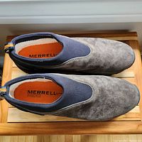 Top-down view of grey suede and navy elastic Merrell moccasin shoes showing the orange insole branding and suede texture.