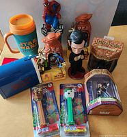 Overhead image showing Star Wars insulated cup, Spiderman figure, Looney Tunes Pez dispensers, cookie jars, Honest Abe bobblehead, and Harry Potter cups.