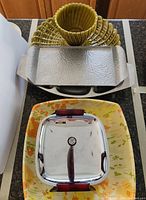 Several stacked metal, stainless steel and ceramic serving trays shown from top view