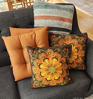 Set of five pillows on dark couch showing variety of vintage floral, solid tufted and striped woven pillows.