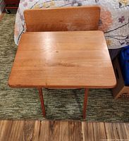 Photo showing one wooden TV tray unfolded with the flat rectangular tray surface and foldable legs visible.