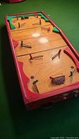 Full view of wooden tabletop hockey game showing overall structure, play surface, and player rods.