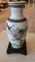 Front view of the porcelain vase showing floral and bird pattern with a white background and black decorative rim.