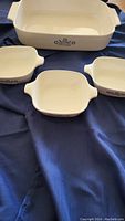 Four piece Corningware ceramic bakeware set; one large rectangular dish and three small square dishes with handles and blue floral pattern