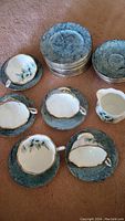 Overview of 5 cups and saucers, 12 dessert plates, and a creamer in Royal Albert bone china with floral and gold design