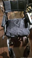 Front view of the wheelchair showcasing black armrests, seat cushion, and padded backrest.
