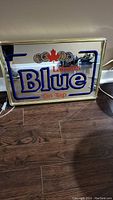 Labatt's Blue lighted mirror wall sign angled upright on floor showing front illuminated face with power cord.