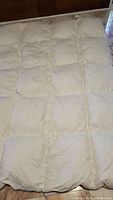 Top view of white, quilted down duvet showing the stitch pattern and overall condition.