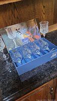Six crystal wine glasses, four still in original Longchamps box with blue interior and illustrated outer packaging.