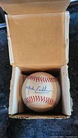 Baseball with clear blue ink signature of Mark Eichhorn, placed in protective cardboard box.