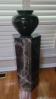 Side view of the faux marble hexagonal pedestal with a black vase on top for illustration only.