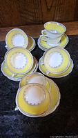 Photo showing multiple porcelain tea cups stacked inside matching saucers, detailed yellow and white color with silver or gray accents