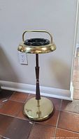 Full view of the vintage ashtray stand showing the brass base, wooden midsection and black ashtray with brass handle.