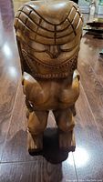 Front view of the hand carved tiki statue showing detailed facial features and body posture.