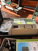 White Cricut Expression cutter device with display screen and multiple buttons for operation, shown with clear lid/tabletop setting.