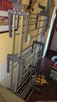 Full view of the large plastic and metal clothes drying rack showing its folded state and multiple bars.