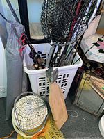 Front view of laundry basket filled with fishing rods, reels, nets and other accessories