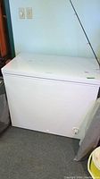 Front view of white Frigidaire chest freezer showing top lid and side panels.