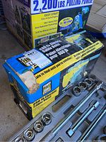 Box of Power Fist 880 lb Electric Cable Hoist showing printed specifications and branding, partially damaged