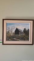 Front view of the framed and matted oil painting showing the log cabin and surrounding trees.