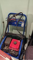 Full view of a blue frame power washer with a red Mitsubishi engine, attached wand and hoses coiled on the frame.
