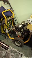 Full view of pressure washer showing yellow frame, engine, wheels and hose