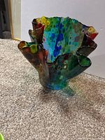 Side view of the multicoloured ruffled art glass vase showing the vibrant polka dot pattern and shape