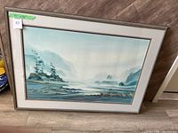 Front view of large framed landscape artwork showing tranquil water, trees, mist, and mountains in blue and green tones.