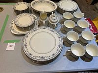 Full view of the Bellemeade Minton bone china set including plates, cups, serving pieces all with blue floral design and silver trim.