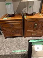 Front view of two Asian style wooden end tables side by side, each topped with table lamps, showcasing overall design, motifs and hardware