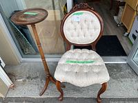 Vintage Victorian chair with upholstered tufted cream floral fabric and dark carved wood frame, front view.
