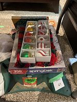 Photo showing two sets of boxed Christmas ornament place card holders and the puzzle box on top of the Christmas tree stand.