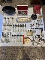 Full assortment laid out on a table showing cutlery, bowls, napkin holders, and trays