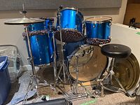 Full view of blue drum set including bass drum, toms, floor tom, cymbals, stool, and stands.