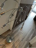 Full view of the floor lamp showing the weighted round base and multiple gooseneck arms extending upwards and outwards, each ending with a light bulb socket with clear bulbs.